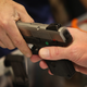Two men lovingly caress a gun together.